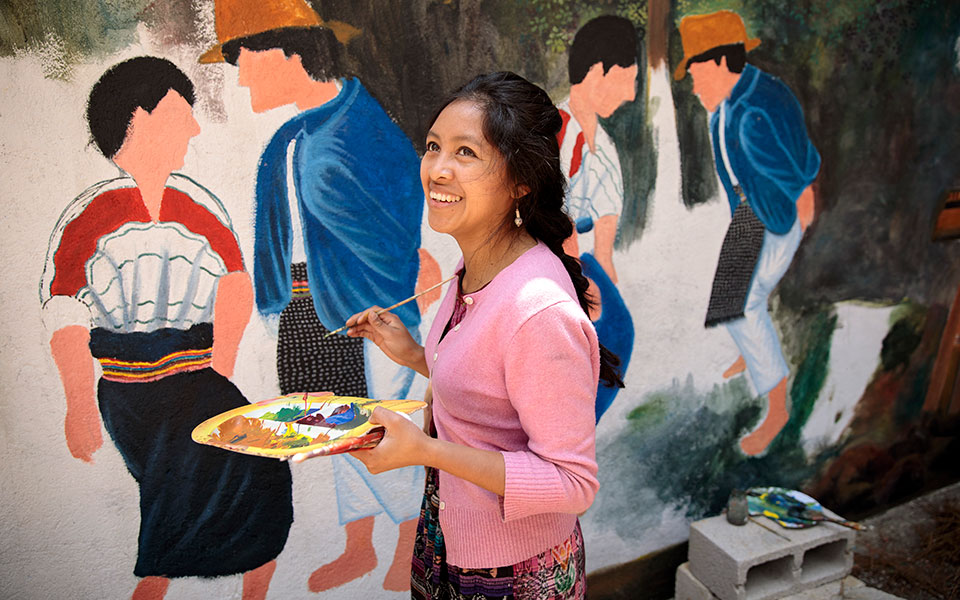 An indigenous woman paints a mural in her community in Guatemala. Photo: UN Women/Ryan Brown